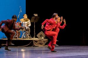 LED dancers Colleen Loverde, Daniel Ojeda, and Tony Carnell perform in front of percussionist Chuck Palmer on the Morrison Center Stage.